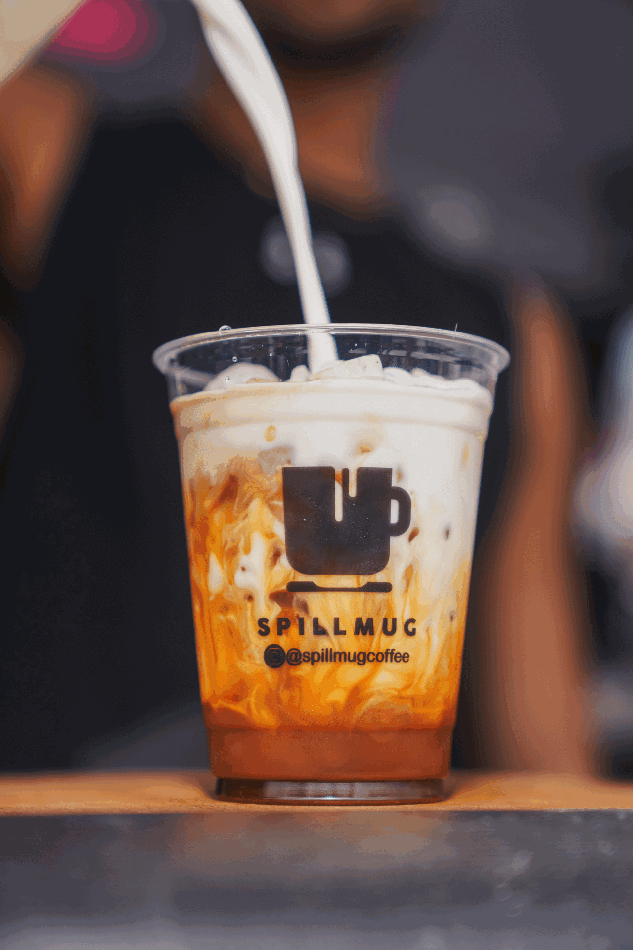 Milk being poured into a Spillmug iced coffee at a mobile coffee bar event in Miami